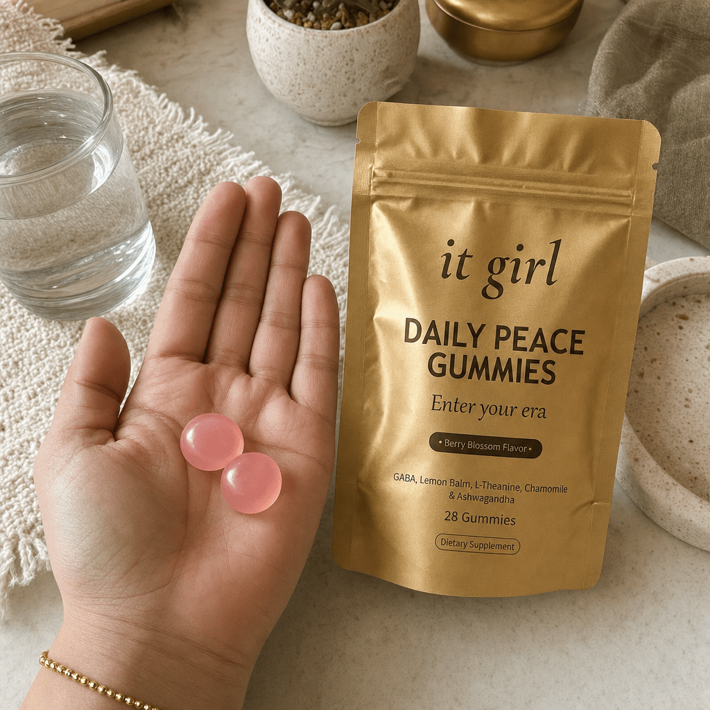 Open palm holding two Daily Peace gummies beside the matte gold pouch and a glass of water, the GABA and L-Theanine signal given directly