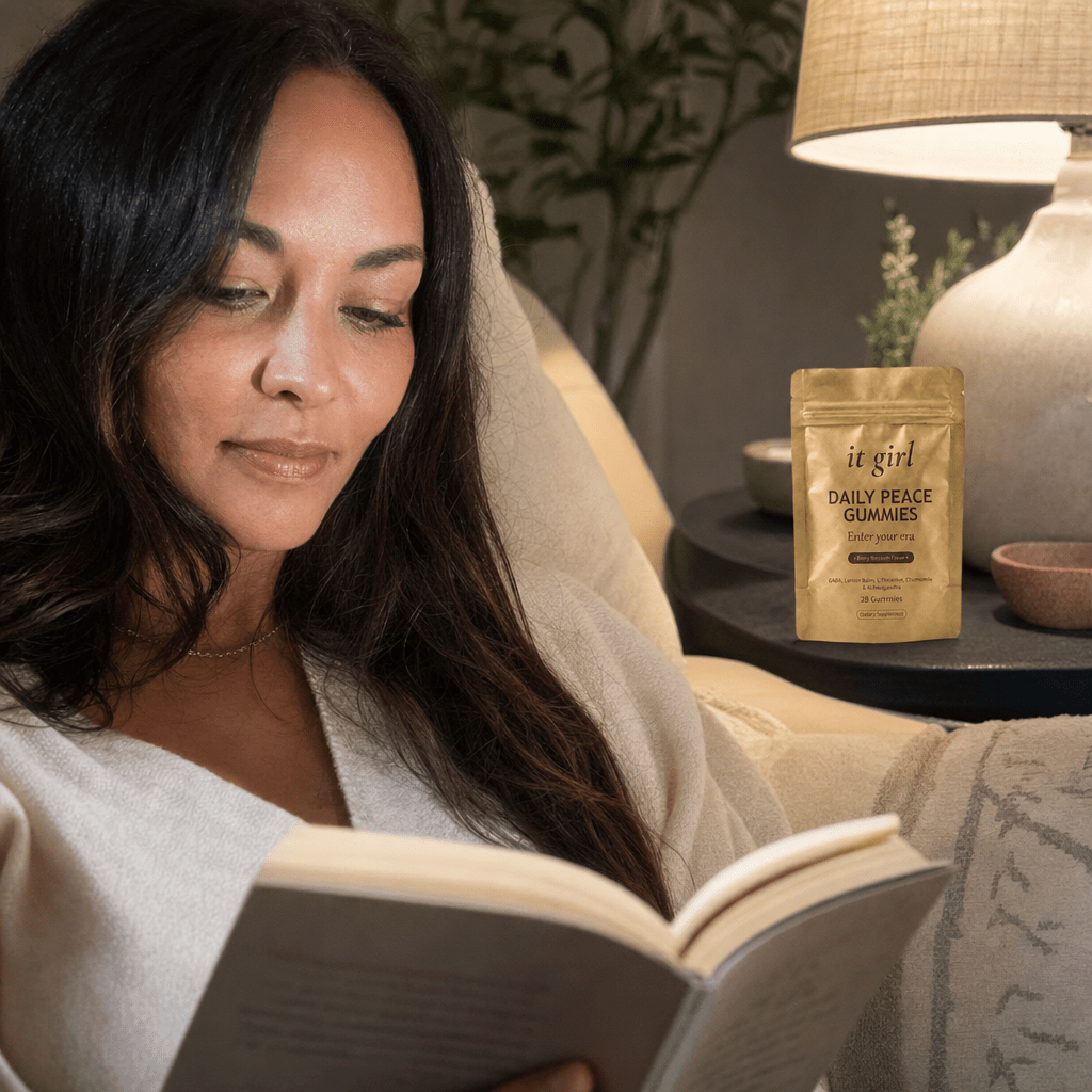 Mother present and clear-eyed reading on the couch at night, no fog, the gold Daily Peace pouch resting subtly nearby