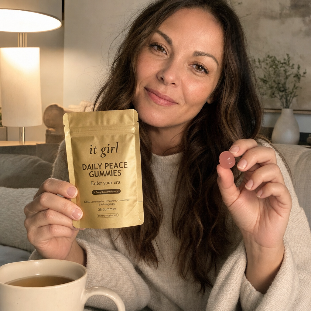 Lauren Hartley relaxed on a couch in evening lamplight holding the It Girl Daily Peace pouch and a single pink gummy, calm and unbraced at the end of the day