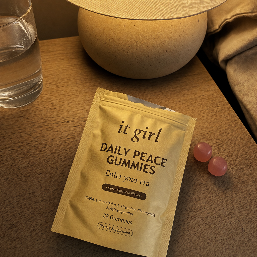 The real gold It Girl Daily Peace pouch opened on a warm evening nightstand beside a calm berry-blossom gummy and a glass of water, the drained calm signal handed back