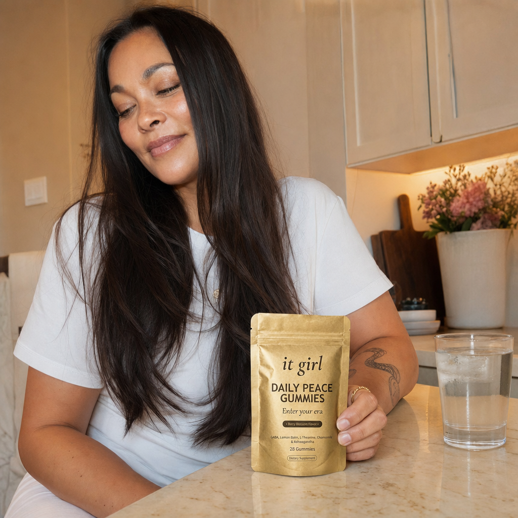Restored woman in her fifties in her early-evening kitchen at the moment the wine pull would hit, hand resting on the gold Daily Peace pouch and taking a calm exhale instead of reaching for a glass