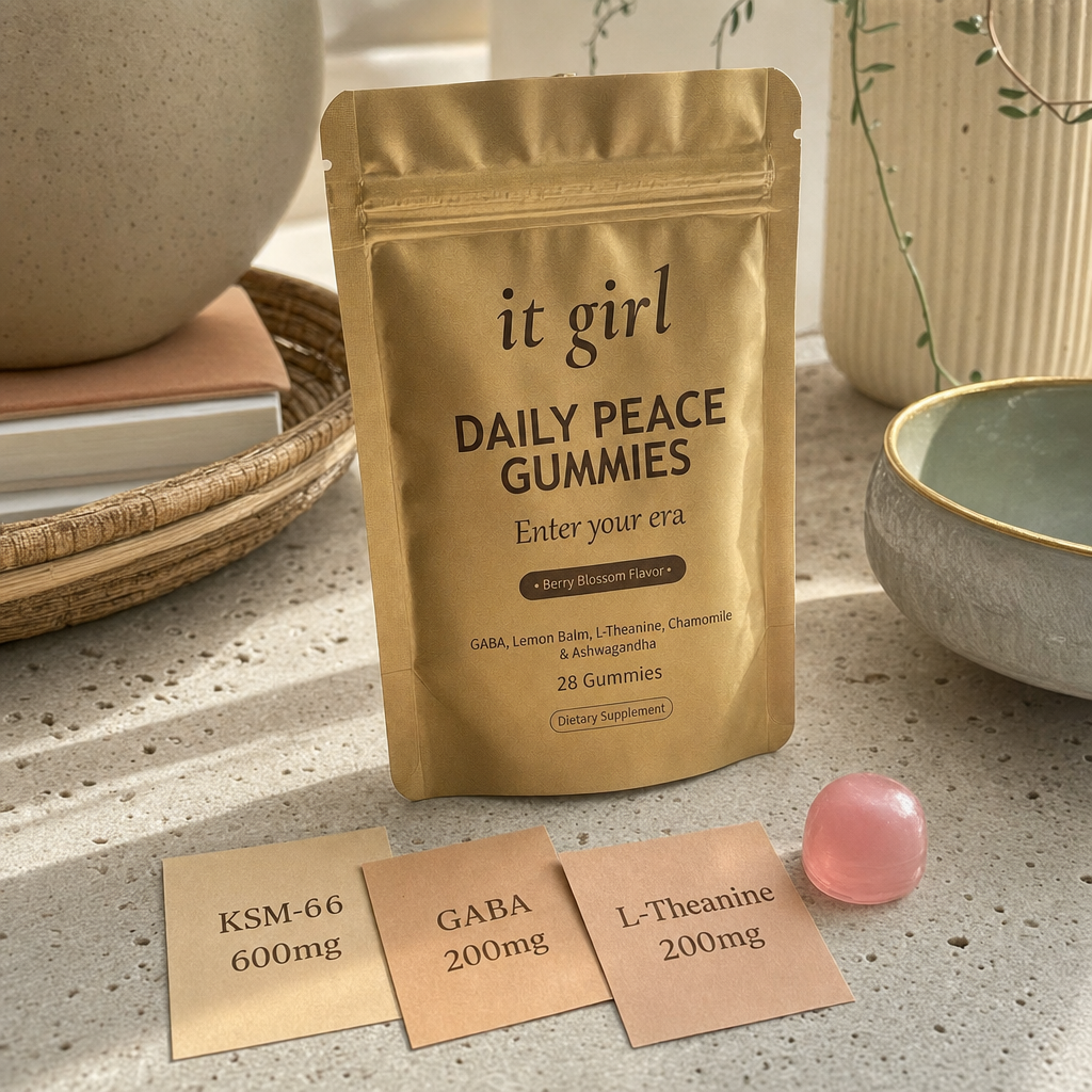 Three warm dose cards reading KSM-66 600mg, GABA 200mg, L-Theanine 200mg beside a single gummy and the gold Daily Peace pouch on a cream surface, two layers in one gummy