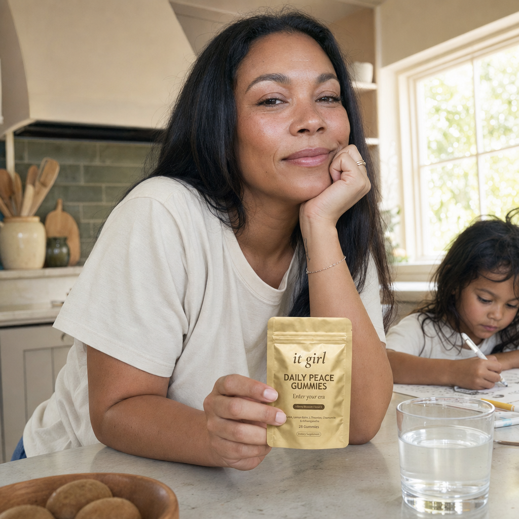 A calm, restored mother about forty steady in her warm afternoon kitchen with her child nearby, the gold Daily Peace pouch on the counter and a glass of water, no wine