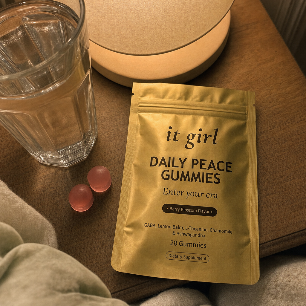 The real gold It Girl Daily Peace pouch opened on a warm evening nightstand beside a calm berry-blossom gummy and a glass of water, the drained calm signal handed back