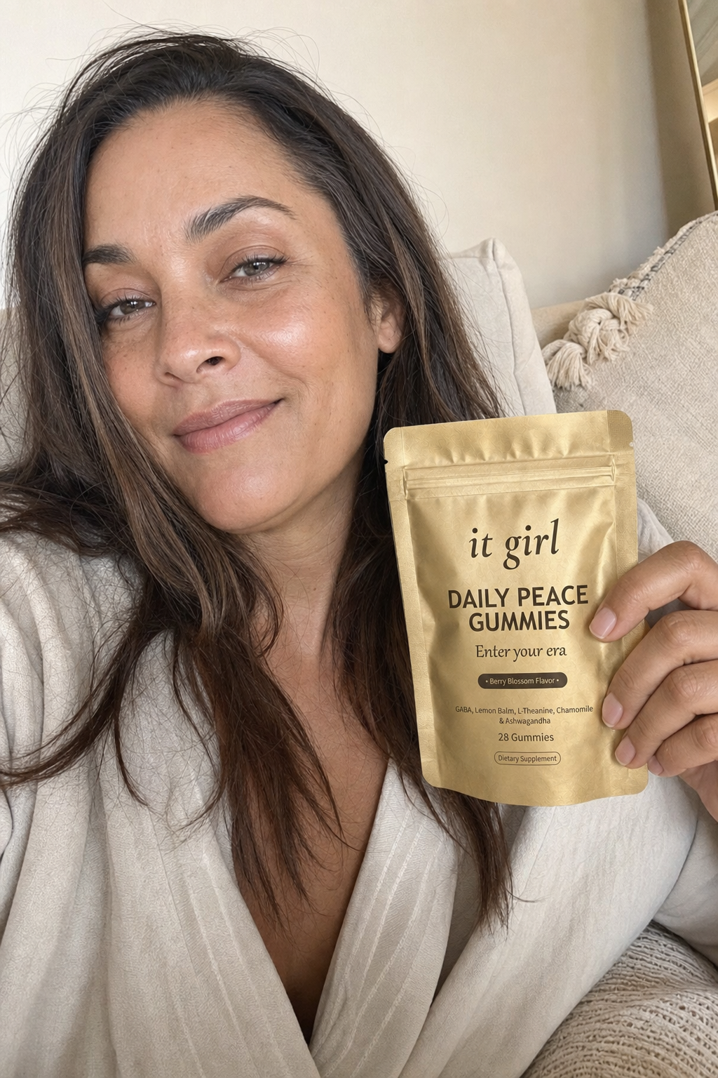 A woman in her forties calm and at ease at home in warm light, the real It Girl Daily Peace pouch resting beside her, the clean calm her five minutes were really for