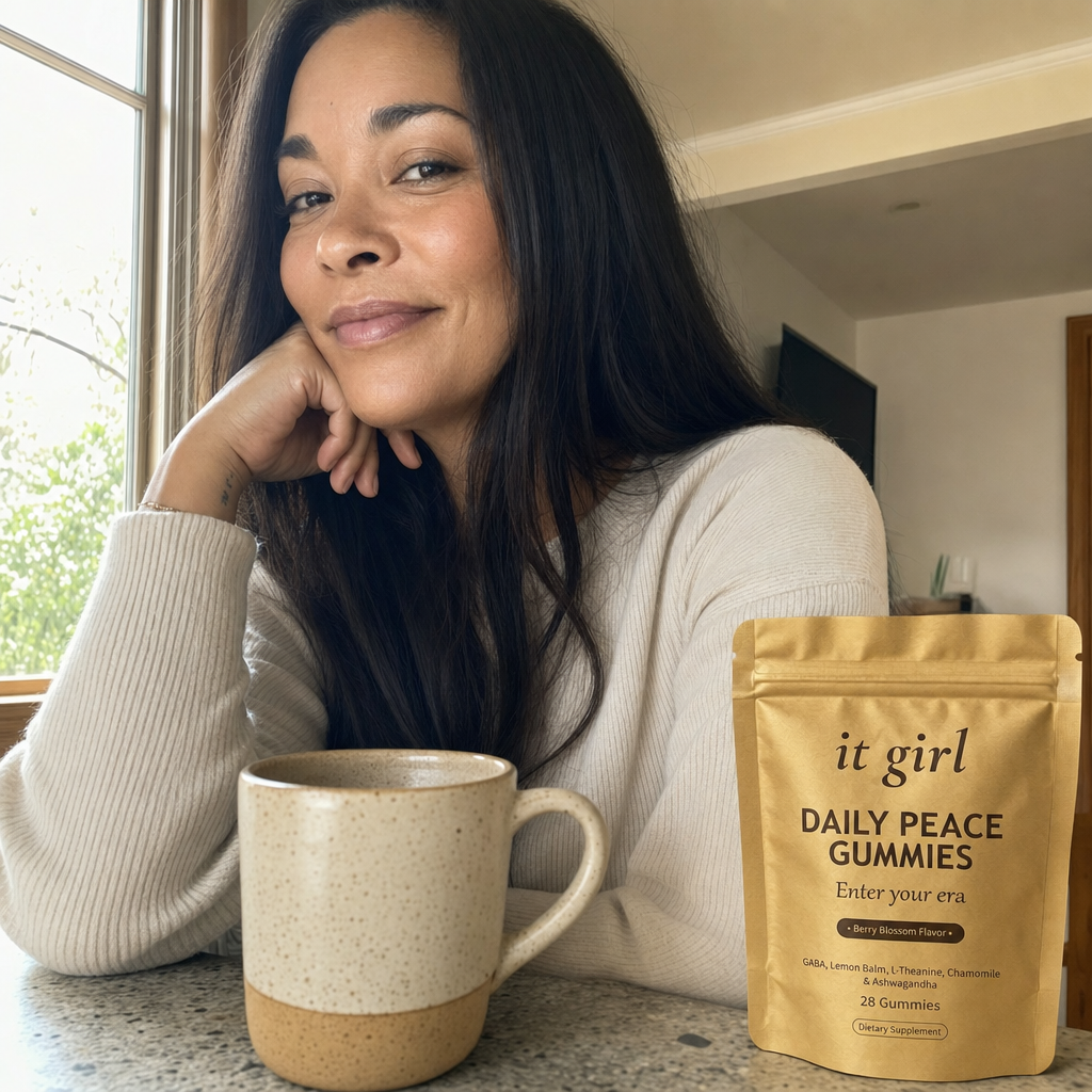 The same woman in her quiet morning moment by a sunny window with a coffee, shoulders down and at ease, the gold It Girl Daily Peace pouch on the counter beside her