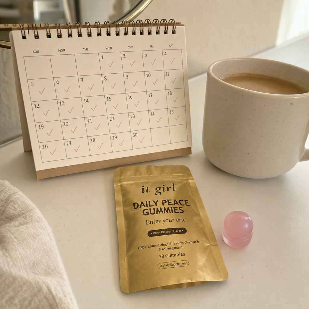 The palm-sized gold It Girl Daily Peace pouch beside a warm-toned month calendar, a whole month of her own calm for about a dollar a day