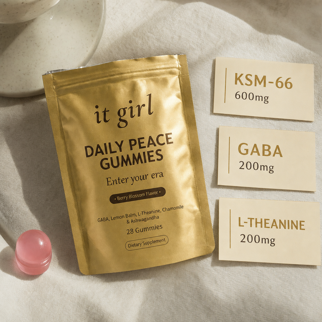 The real matte gold It Girl Daily Peace pouch and a single pink gummy beside three dose cards: KSM-66 600mg, GABA 200mg, L-Theanine 200mg.