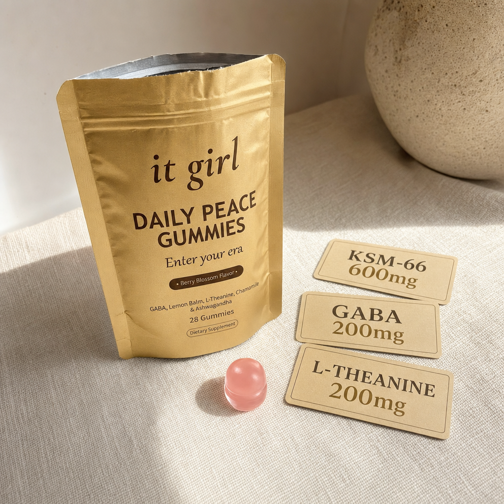 The real matte gold It Girl Daily Peace pouch and a single pink gummy beside three dose cards: KSM-66 600mg, GABA 200mg, L-Theanine 200mg.