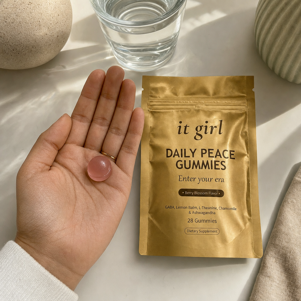 Open palm holding a single pink Daily Peace gummy beside the gold pouch and a glass of water, the GABA and L-Theanine signal that fills the same prescription