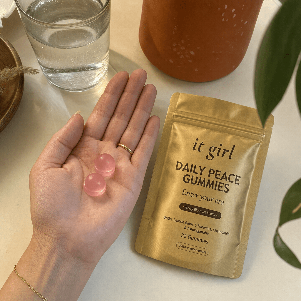 Open palm holding two pink Daily Peace gummies beside the gold pouch and a glass of water, the GABA plus L-Theanine evening signal
