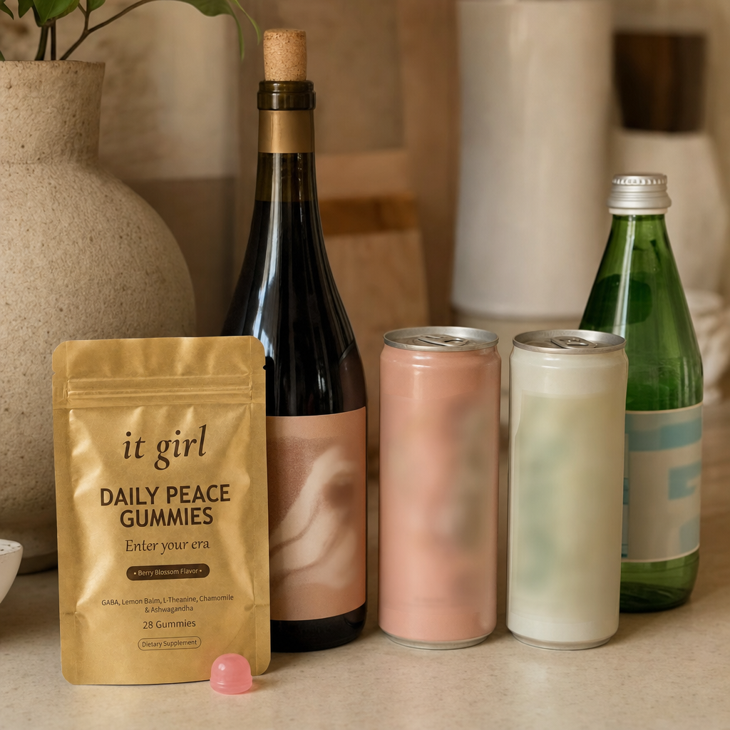 The real It Girl Daily Peace pouch on a warm cream counter beside the untouched wine alternatives, a corked alcohol-free wine bottle and two adaptogen cans, the one that finally goes after the signal instead of the glass