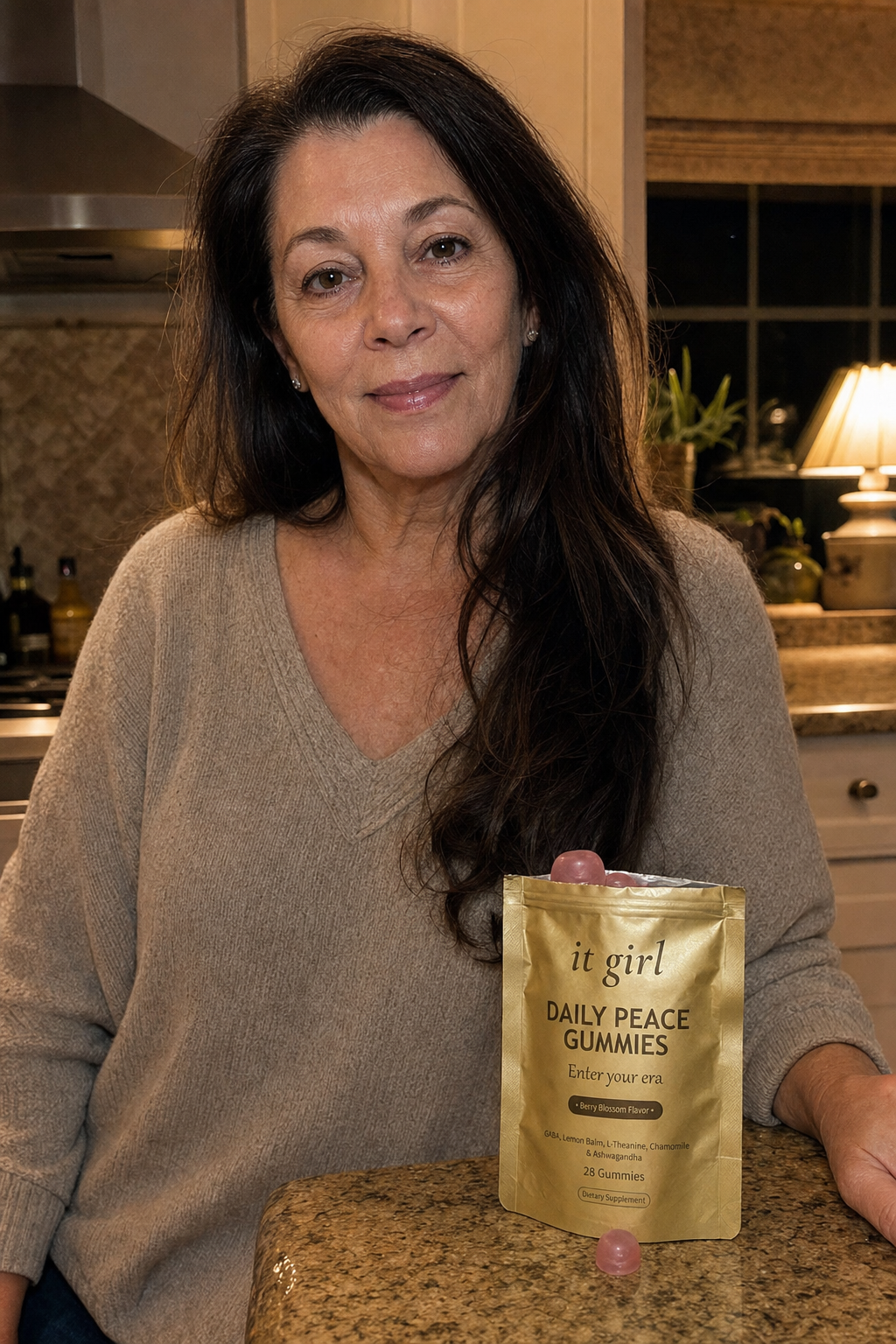 Warm evening kitchen photo of a relaxed woman in her late fifties at ease at the counter with the real gold It Girl Daily Peace pouch resting beside her, top rolled open, the calm she was reaching for handed back directly