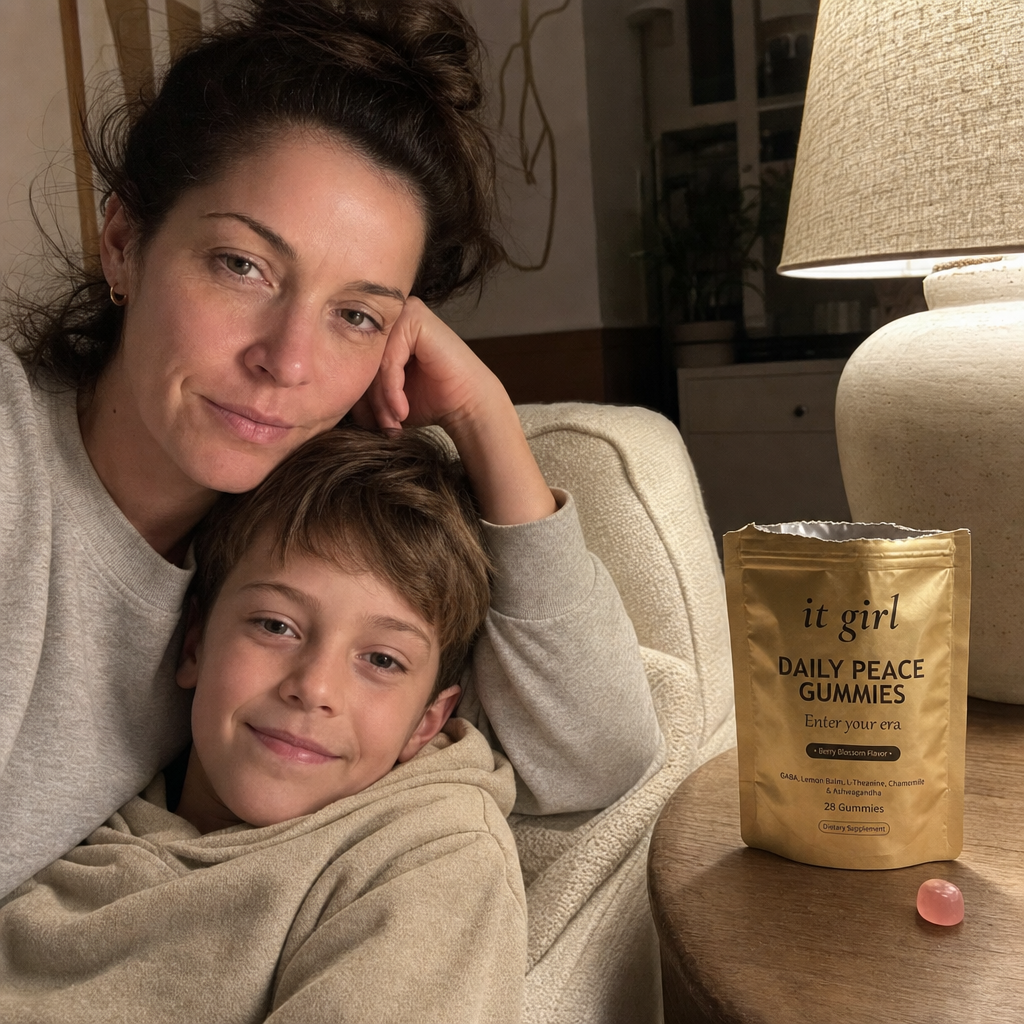 Restored calm mother on the couch with her young son climbing into her lap and staying, the real palm-sized gold It Girl Daily Peace pouch torn open with a loose pink gummy on the side table