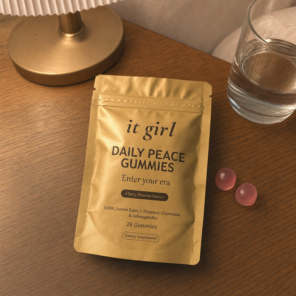 The real gold It Girl Daily Peace pouch opened on a warm evening nightstand beside a calm berry-blossom gummy and a glass of water, the drained calm signal handed back