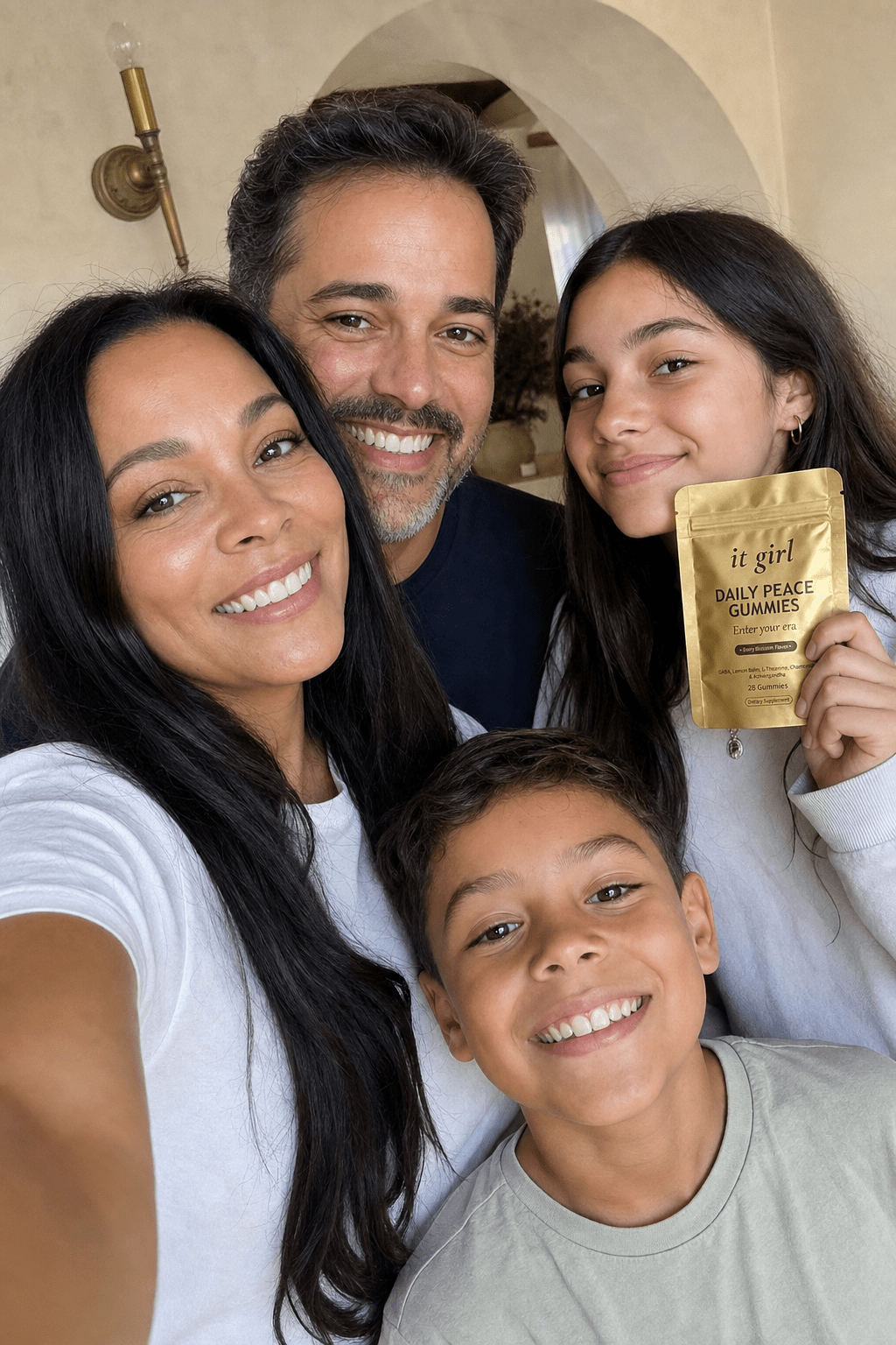 Ultra-realistic candid family selfie: a happy woman in her early 40s with pretty makeup taking a phone selfie with her husband, her daughter holding up the real matte-gold It Girl Daily Peace pouch, and her young son, in warm home light