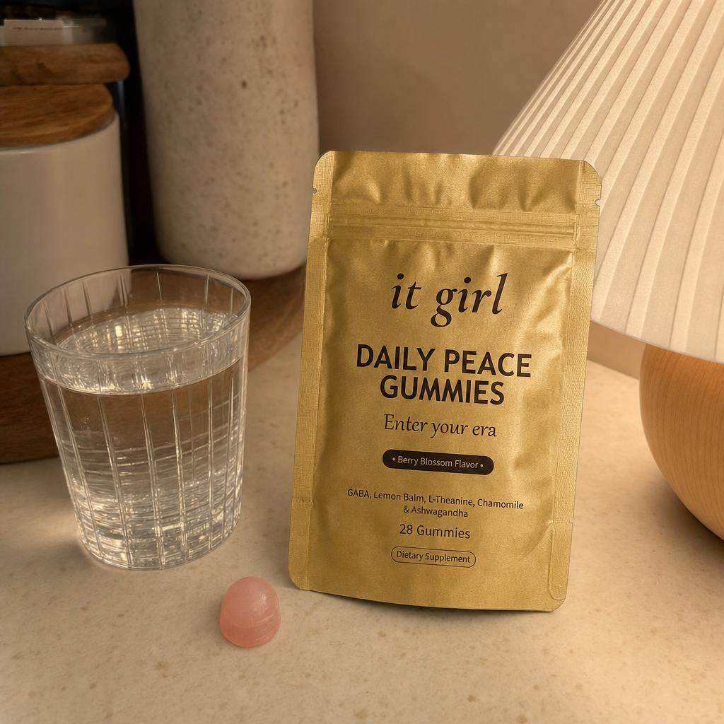 A warm early-evening kitchen counter at the moment the wound-up feeling hits, a glass of water and the real It Girl Daily Peace pouch by a softly glowing lamp