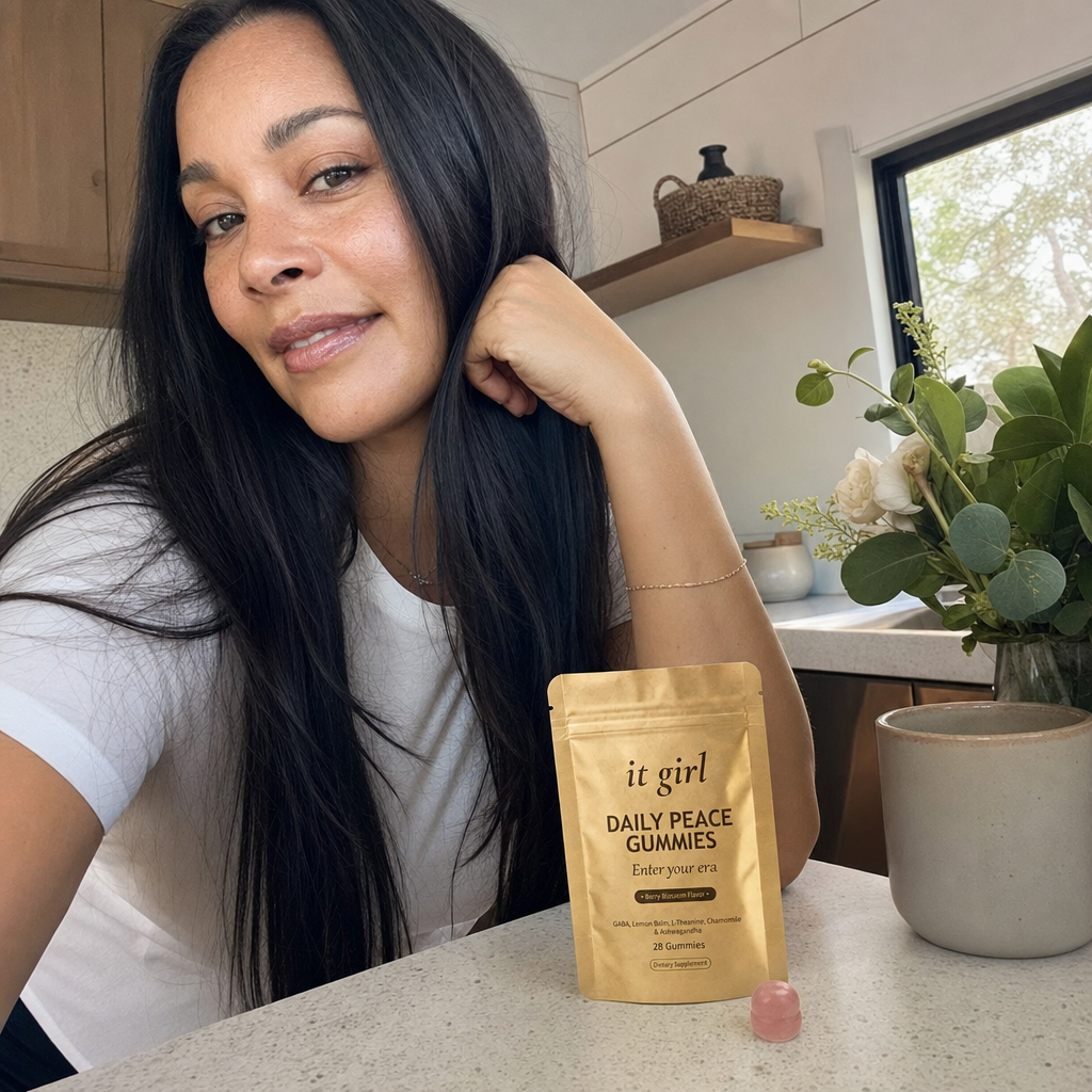The same woman steadier and calm as she goes about her morning, shoulders relaxed, the gold It Girl Daily Peace pouch in frame on the counter