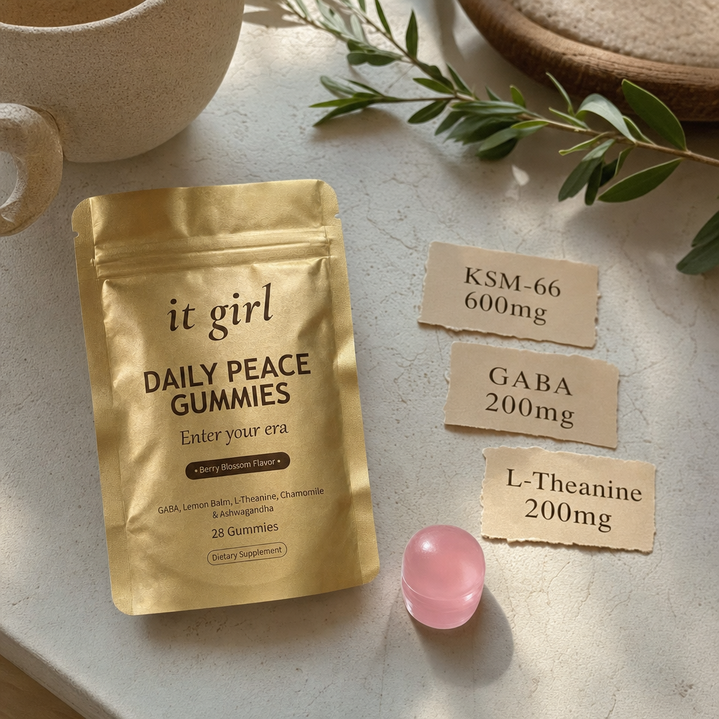 Warm product reveal of the gold It Girl Daily Peace pouch beside a single gummy and three dose cards reading GABA 200mg, L-Theanine 200mg, KSM-66 600mg, the full studied stack