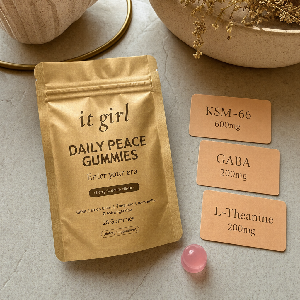 Product reveal: three warm dose cards reading GABA 200mg, L-Theanine 200mg, KSM-66 600mg beside the real gold It Girl Daily Peace pouch and a single gummy on a cream surface, the named studied stack