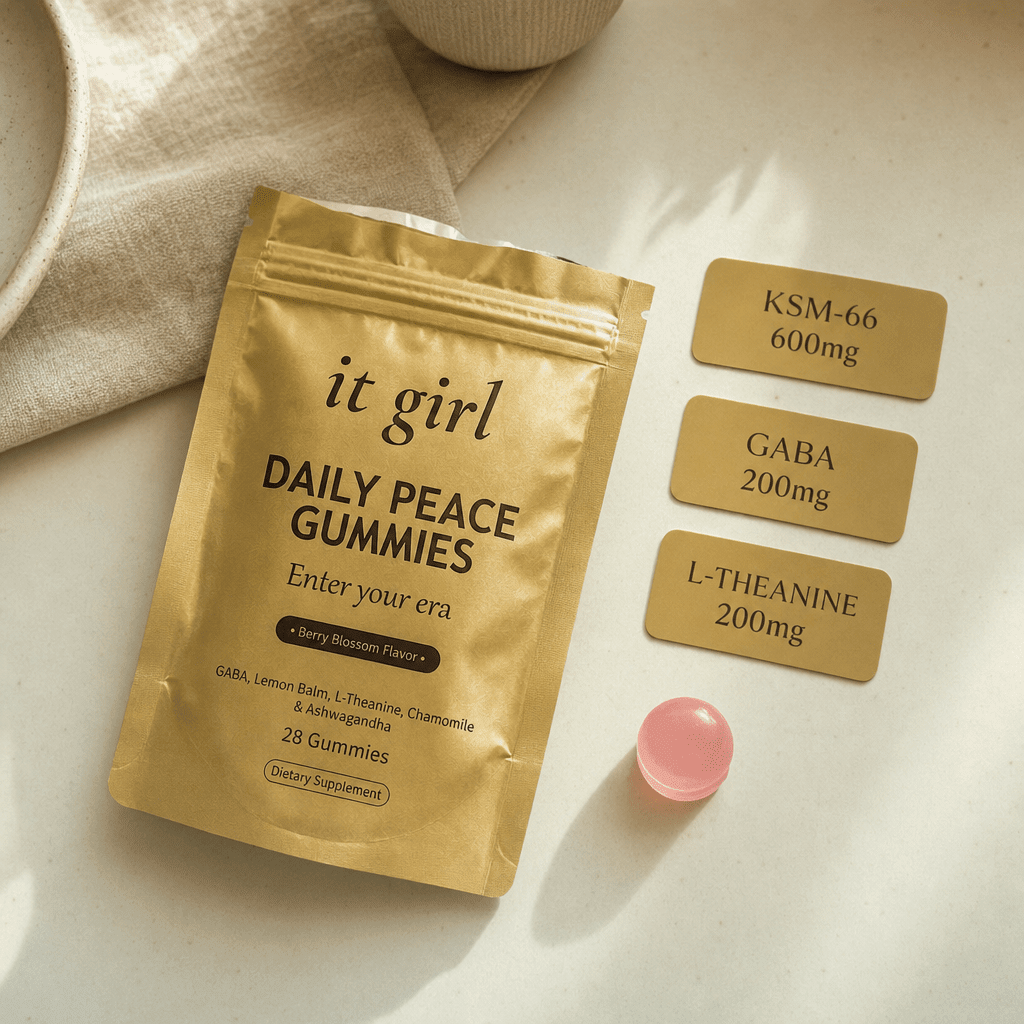 The real matte gold It Girl Daily Peace pouch and a single pink gummy beside three dose cards: KSM-66 600mg, GABA 200mg, L-Theanine 200mg.