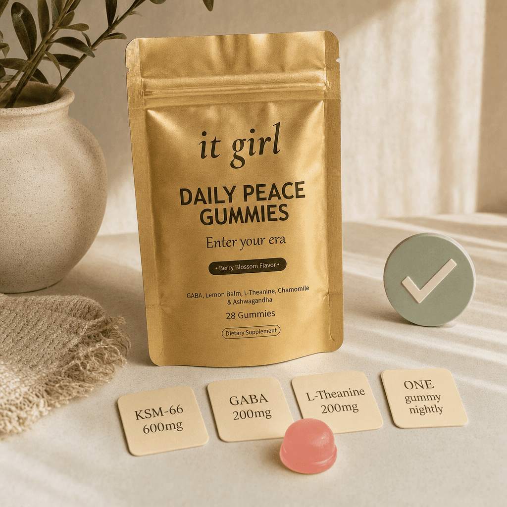 The real matte-gold It Girl Daily Peace pouch with a calm-blue check, a single pink gummy, and three dose cards reading KSM-66 600mg, GABA 200mg, L-Theanine 200mg on a warm cream surface, the same signal delivered clean
