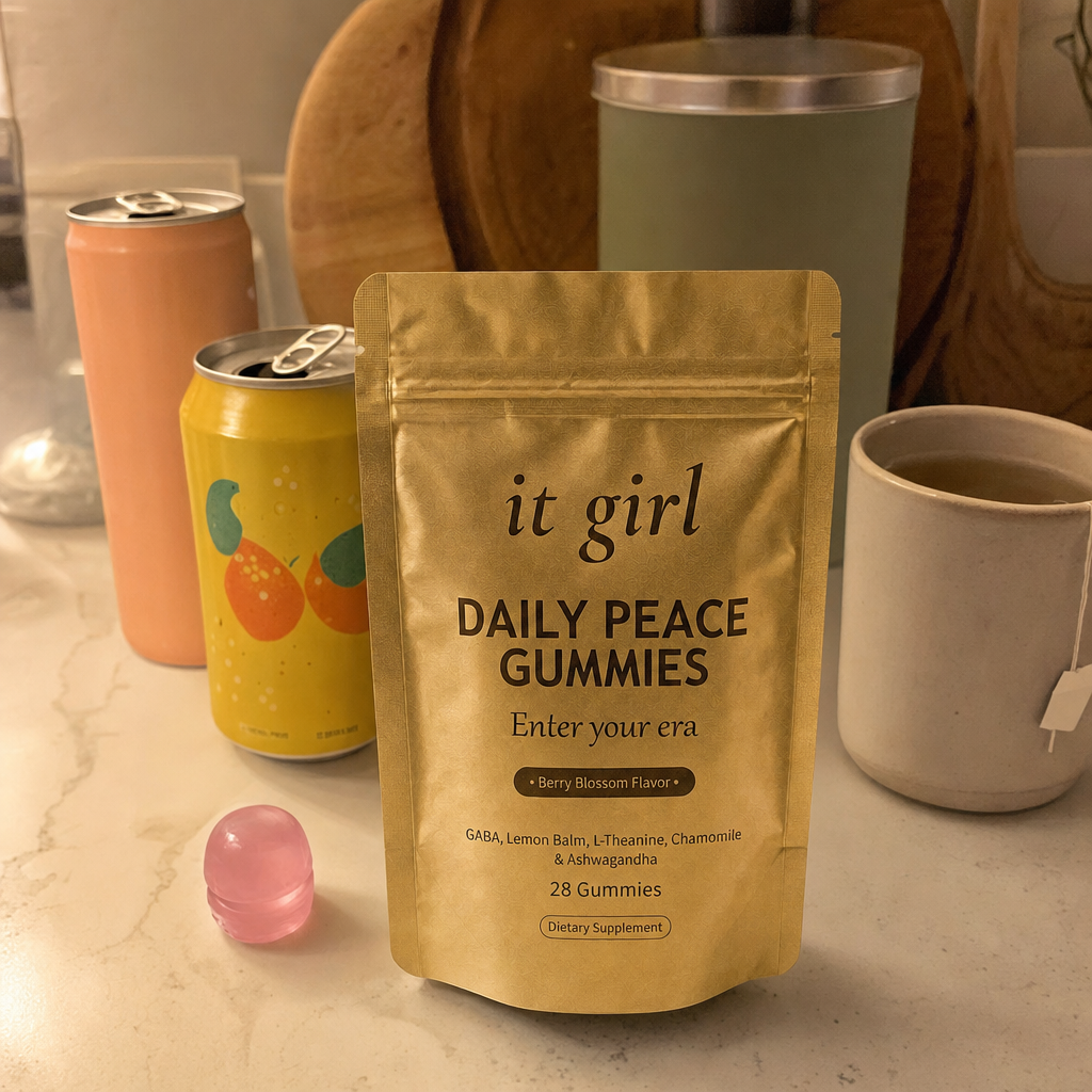 The real matte gold It Girl Daily Peace pouch forward in warm focus on a counter, the abandoned wine swaps, a brightly-colored generic flavored seltzer can and an adaptogen drink and a mug of cold tea, pushed aside behind it