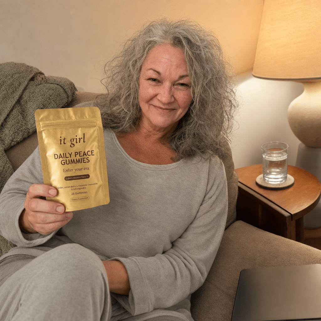 Same woman relaxed on her couch in the evening, laptop closed and present, a glass of water and the gold Daily Peace pouch on the side table instead of a glass of wine