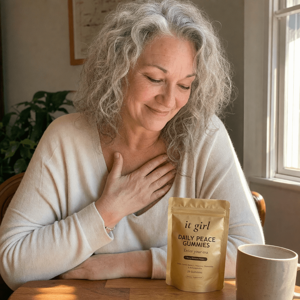 Same woman in a quiet moment of self-forgiveness by a window in warm morning light, a hand over her heart, the gold Daily Peace pouch resting nearby
