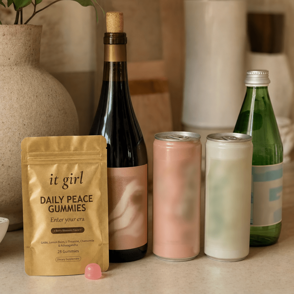 The real It Girl Daily Peace pouch on a warm cream counter beside the untouched wine alternatives, a corked alcohol-free wine bottle and two adaptogen cans, the one that finally goes after the signal instead of the glass
