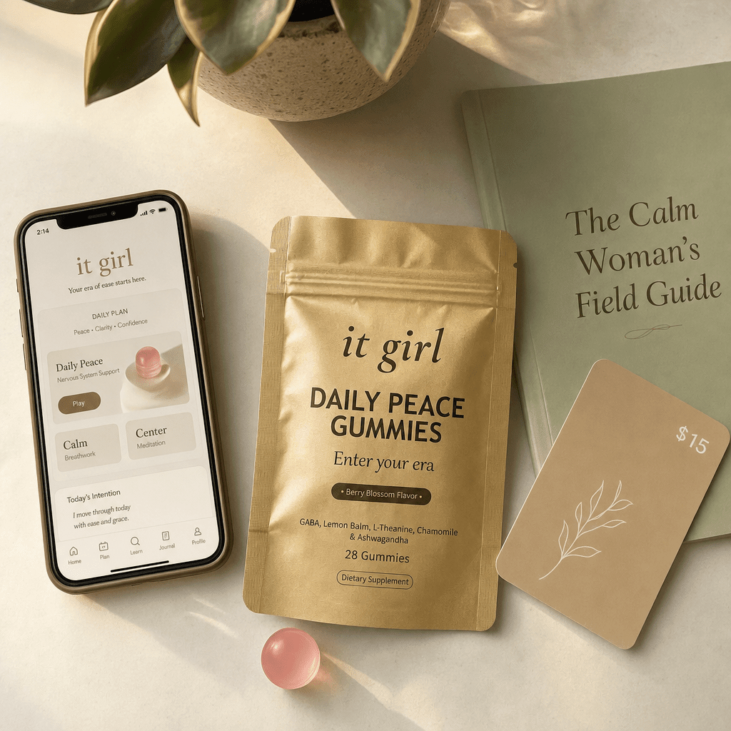 The real It Girl Daily Peace bundle on warm cream, the gold pouch front and center with the It Girl app on a phone, the Calm Woman's Field Guide booklet and a fifteen-dollar gift card, a whole month of calm for about a dollar a day
