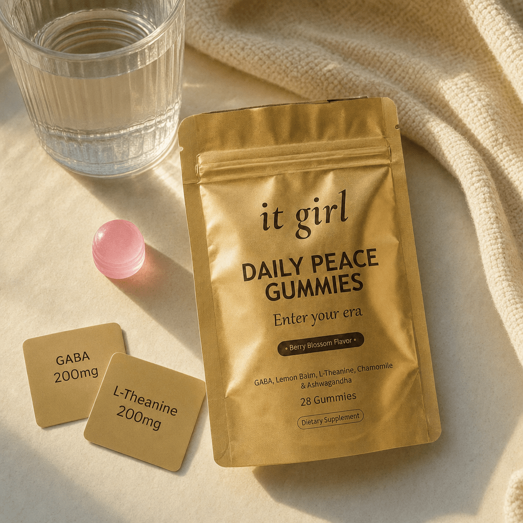 The real It Girl Daily Peace pouch laid open with one pink gummy beside it and two warm dose cards reading GABA 200mg and L-Theanine 200mg on a cream surface in soft evening light
