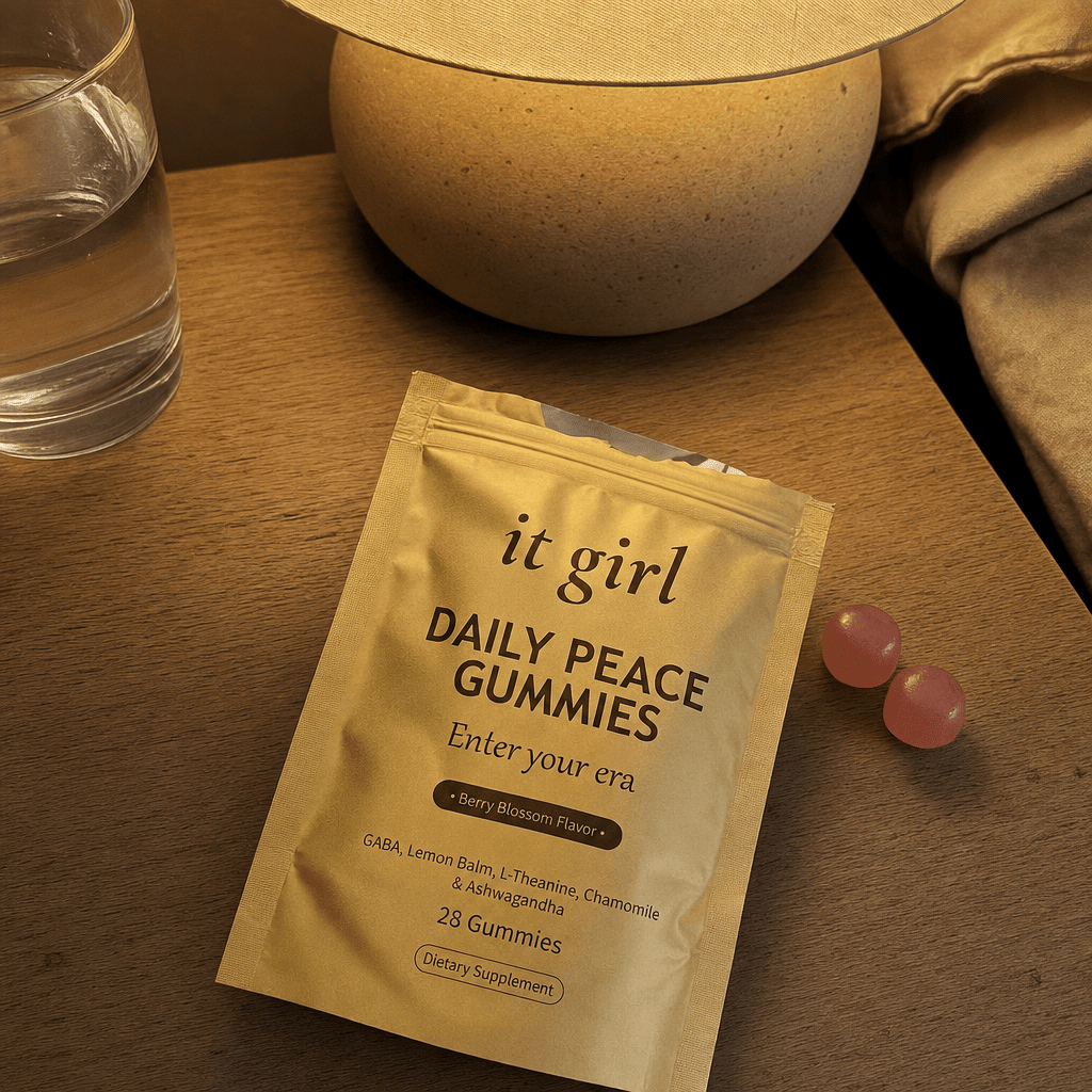 The real gold It Girl Daily Peace pouch opened on a warm evening nightstand beside a calm berry-blossom gummy and a glass of water, the drained calm signal handed back