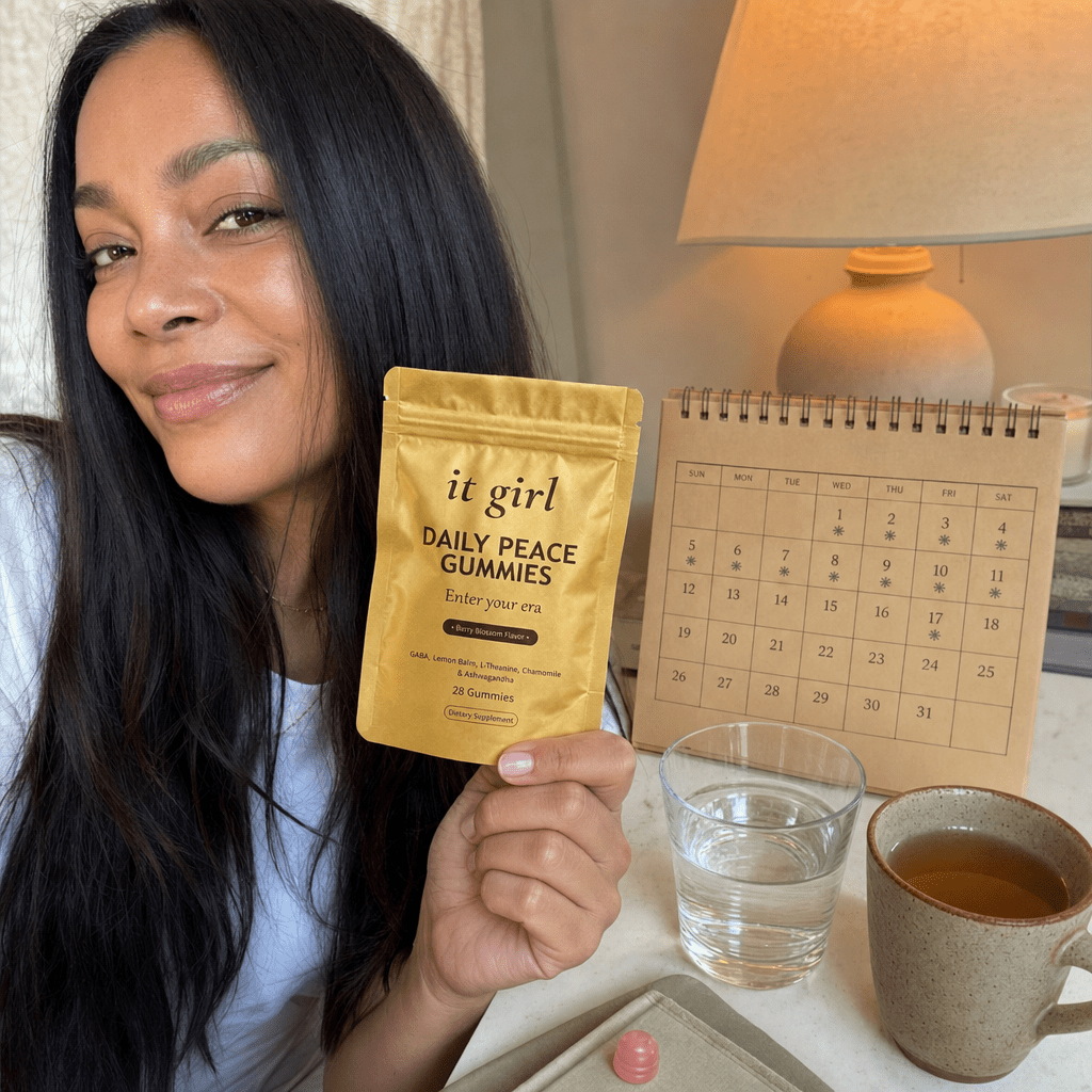 The palm-sized gold Daily Peace pouch beside a month calendar on a cream surface, a whole month of calm for about a dollar a day