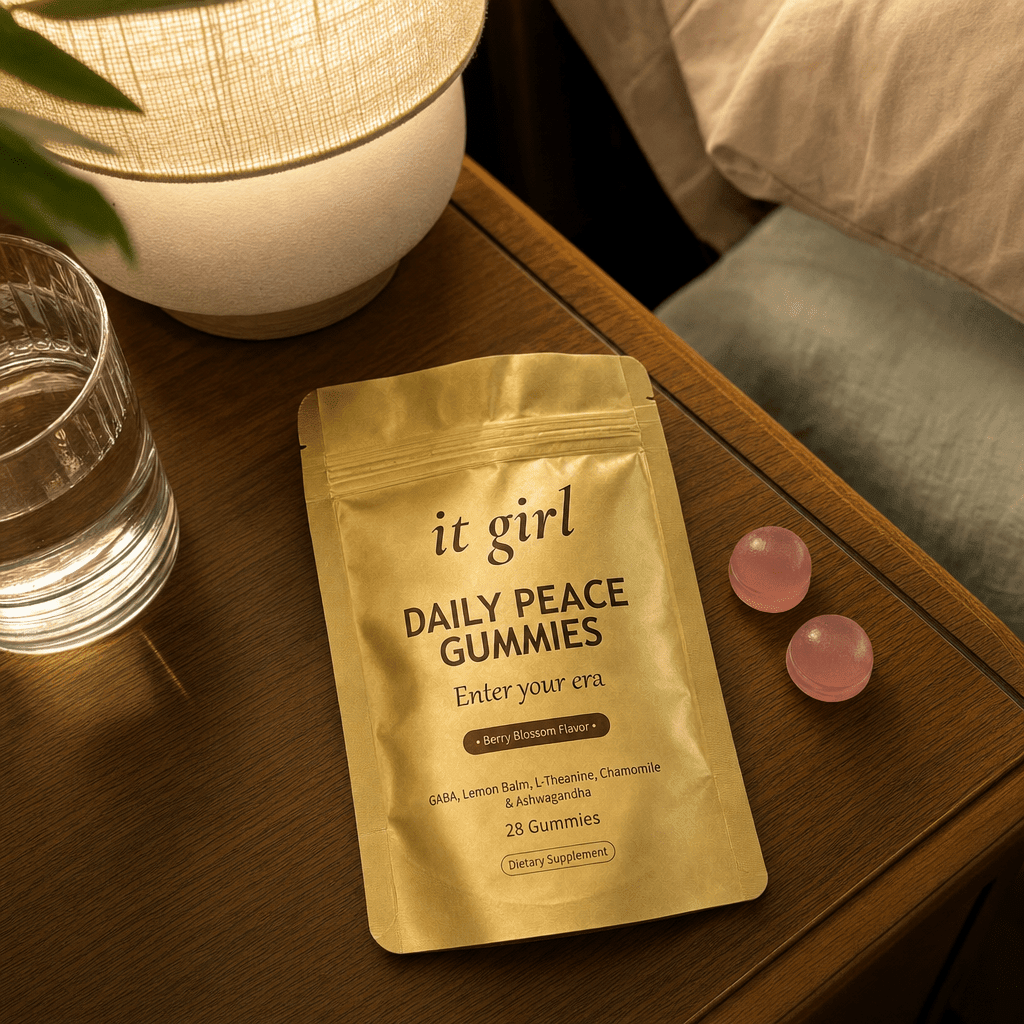 The real gold It Girl Daily Peace pouch opened on a warm evening nightstand beside a calm berry-blossom gummy and a glass of water, the drained calm signal handed back