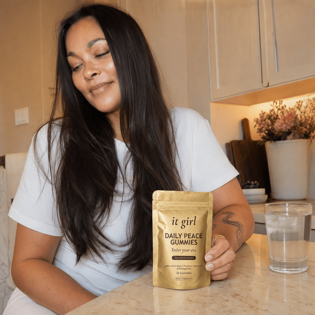 Restored woman in her fifties in her early-evening kitchen at the moment the wine pull would hit, hand resting on the gold Daily Peace pouch and taking a calm exhale instead of reaching for a glass