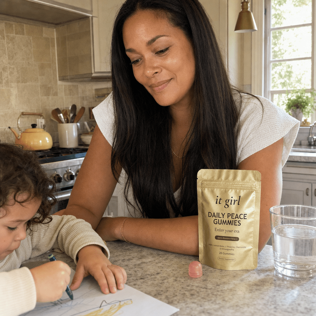 A calm, restored mother about forty steady in her warm afternoon kitchen with her child nearby, the gold Daily Peace pouch on the counter and a glass of water, no wine