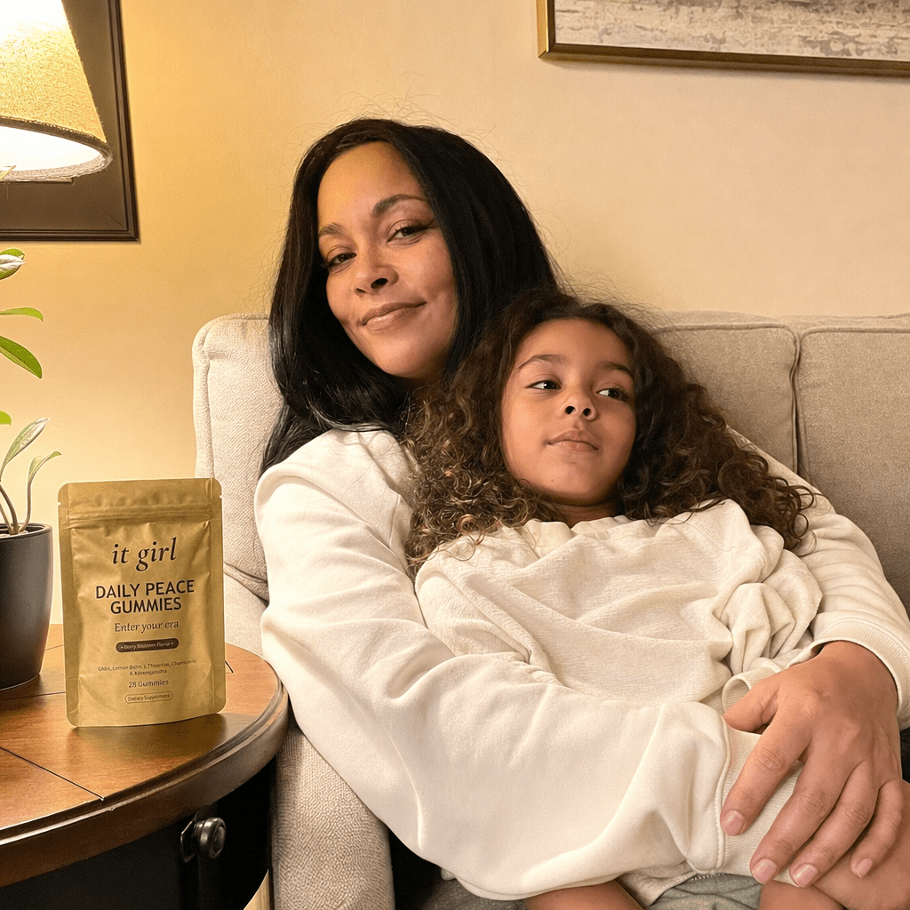 A present mother on the couch in warm lamplight with her nine-year-old climbed into her lap, her phone nowhere in sight, the gold Daily Peace pouch resting on the side table