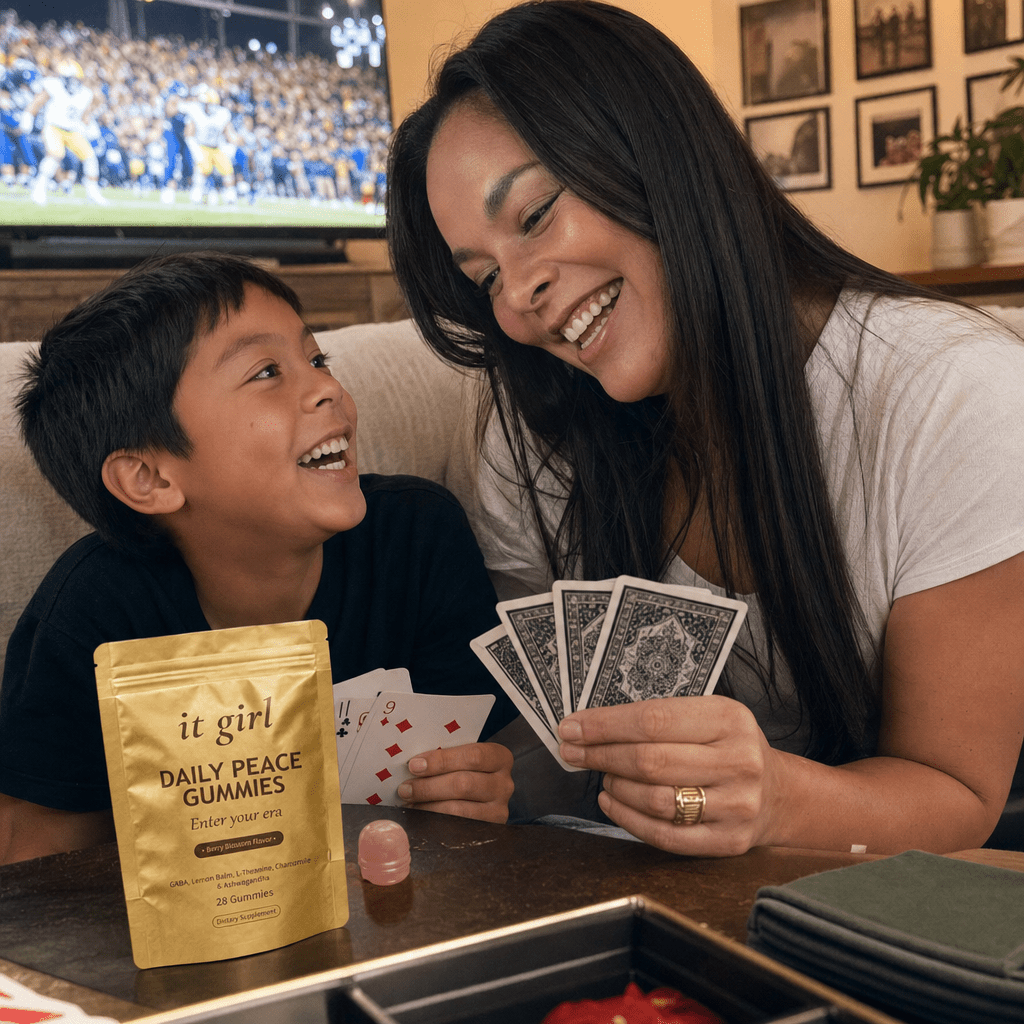 A mom genuinely present and laughing with her family on the couch during game night, the real It Girl Daily Peace pouch resting on a side table