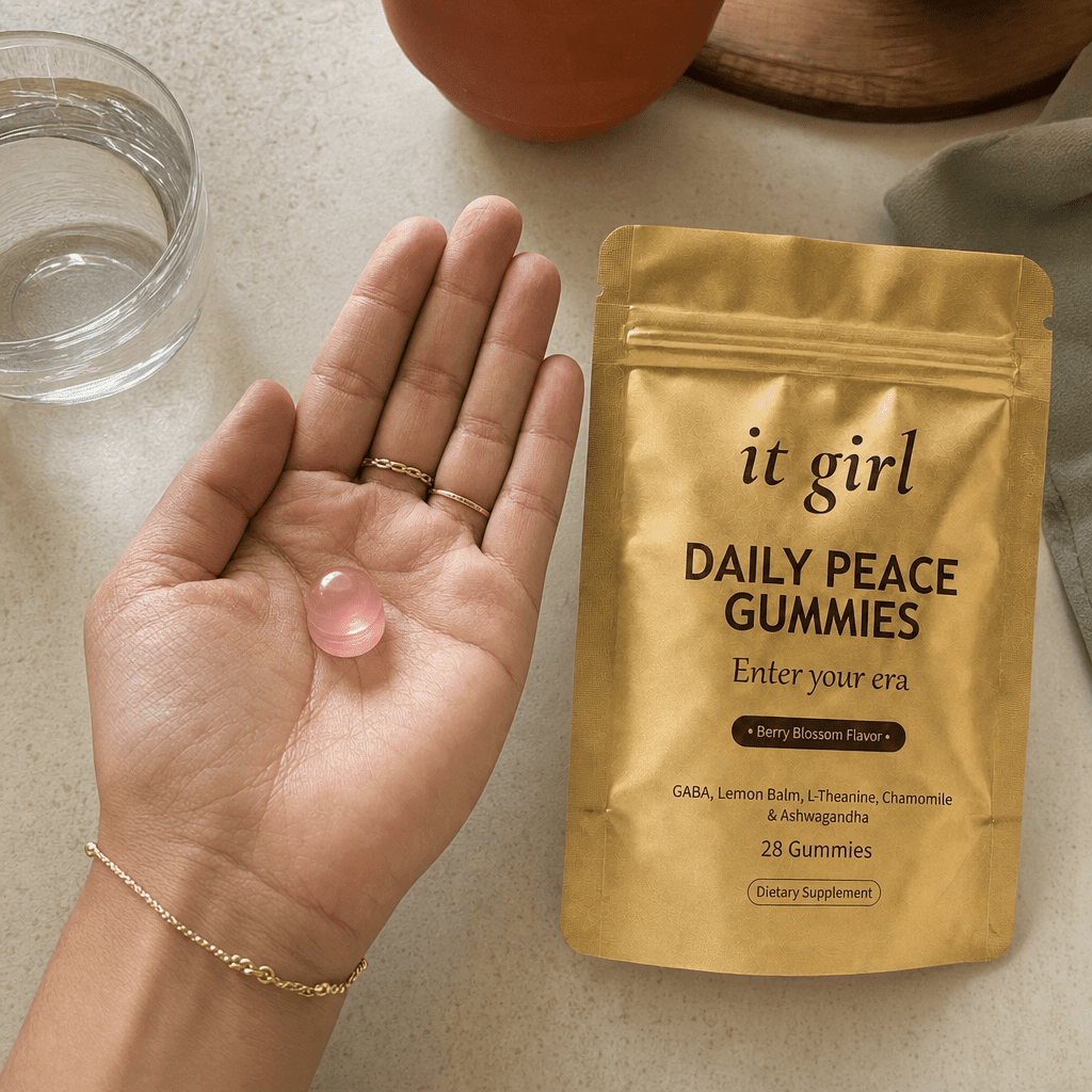 Open palm holding a single pink Daily Peace gummy beside the gold pouch and a glass of water on a cream counter, the GABA and L-Theanine calm signal handed back
