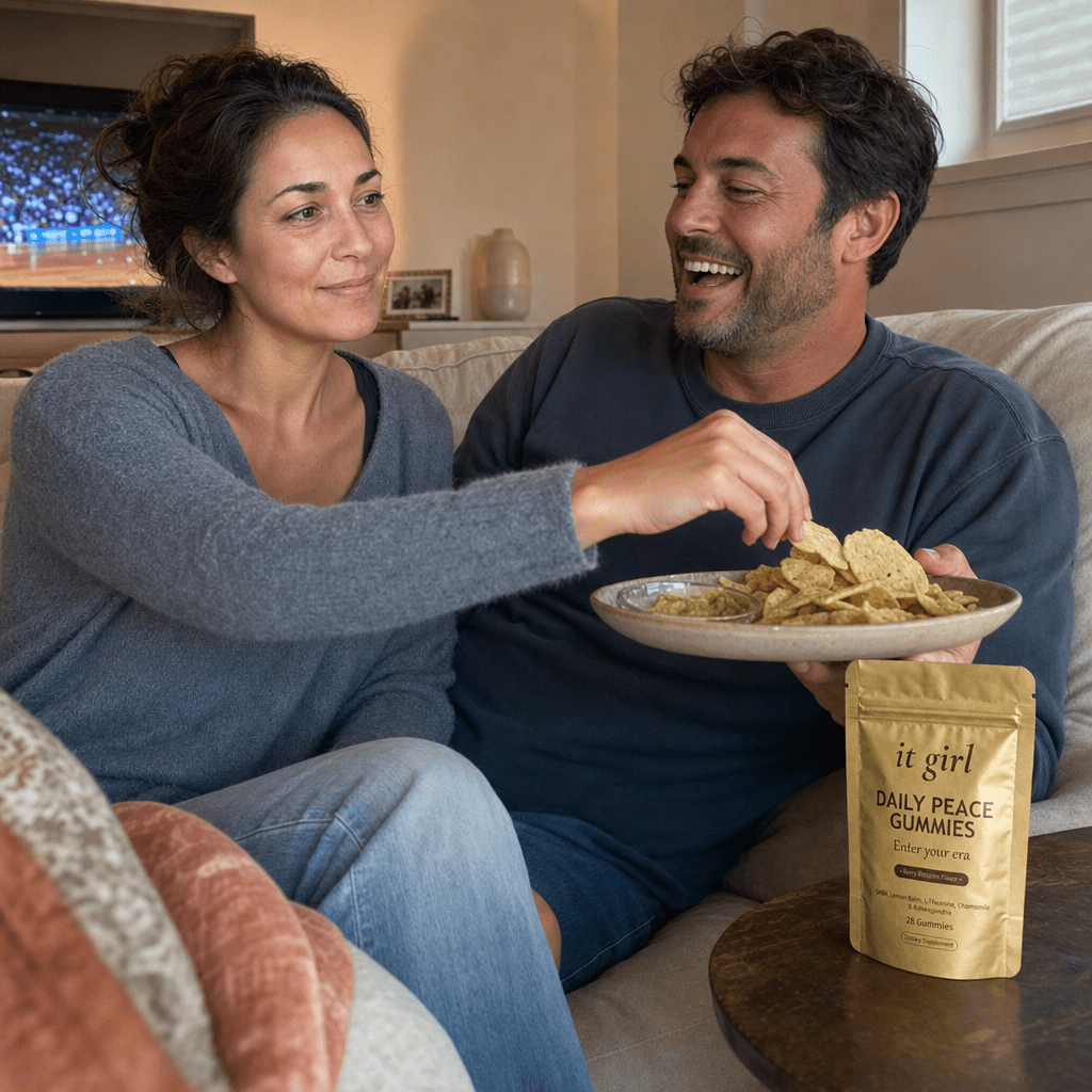 The same working mom back in her own living room on game night, done-up and laughing as she steals a chip off her husband's plate, the gold Daily Peace pouch resting on the side table
