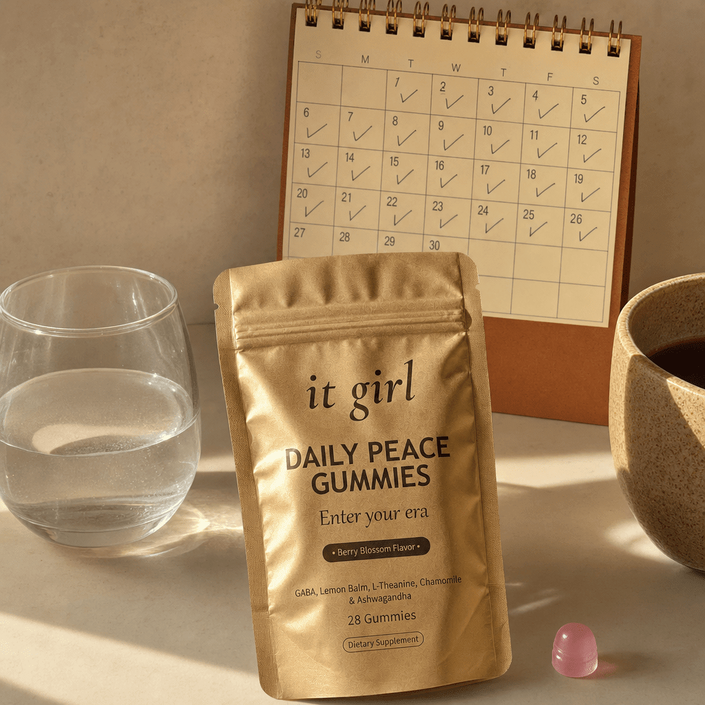 The palm-sized It Girl Daily Peace pouch beside a warm-toned desk calendar with a full month lightly marked, a whole month of her own calm for about a dollar a day