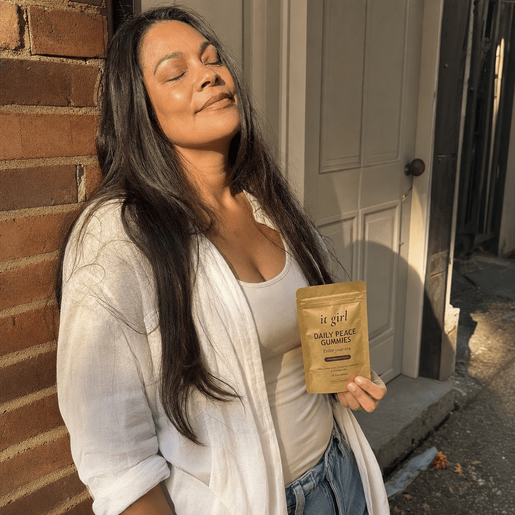 A woman in her forties stepping outside for her quiet five minutes, leaning against a sunlit doorway with her eyes closed, shoulders dropping as she exhales
