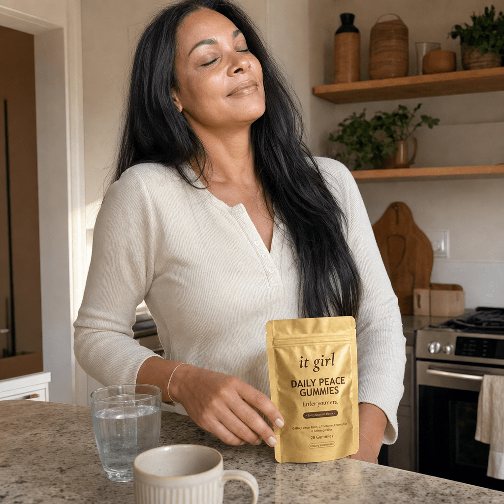 Woman in her late forties in her early-morning kitchen, hand resting easy on the gold Daily Peace pouch on the counter while she takes a slow calm exhale instead of reaching, soft warm light