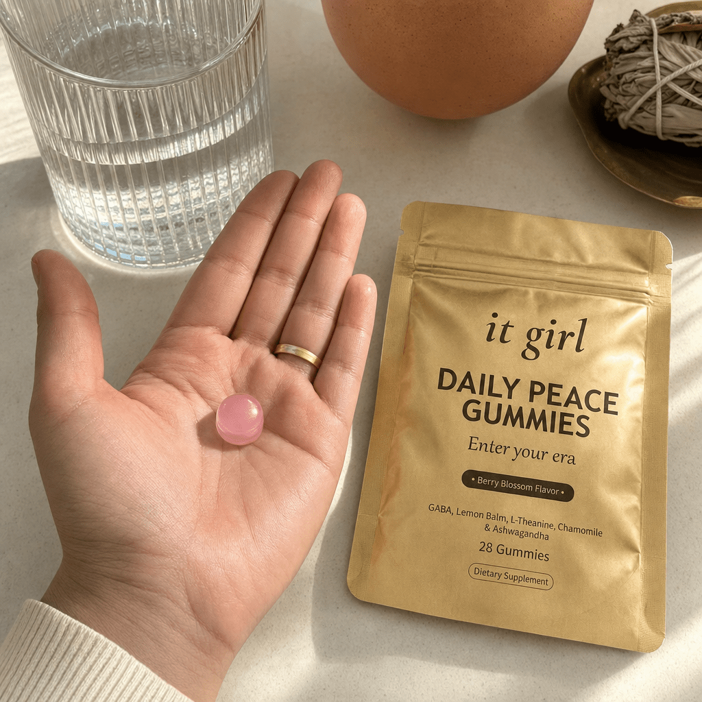Open palm holding a single pink Daily Peace gummy beside the gold pouch and a glass of water on a cream surface, the GABA and L-Theanine calm signal