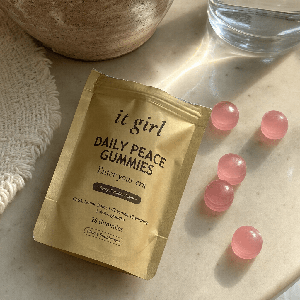 An opened It Girl Daily Peace pouch with berry-blossom gummies and a glass of water on a warm cream surface