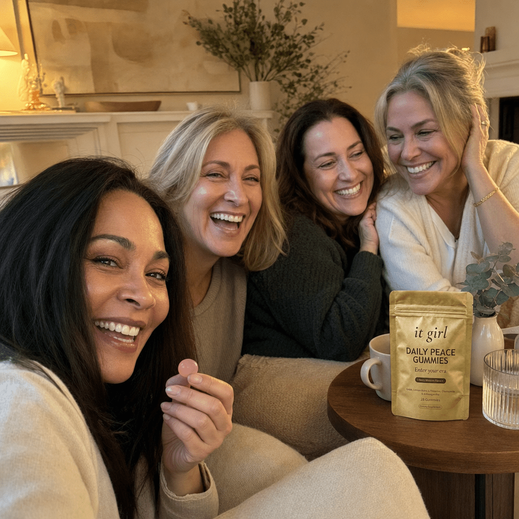 Relaxed group of women in their forties to sixties laughing together with tea and water in a warm living room, a gold Daily Peace pouch resting nearby, not the only one