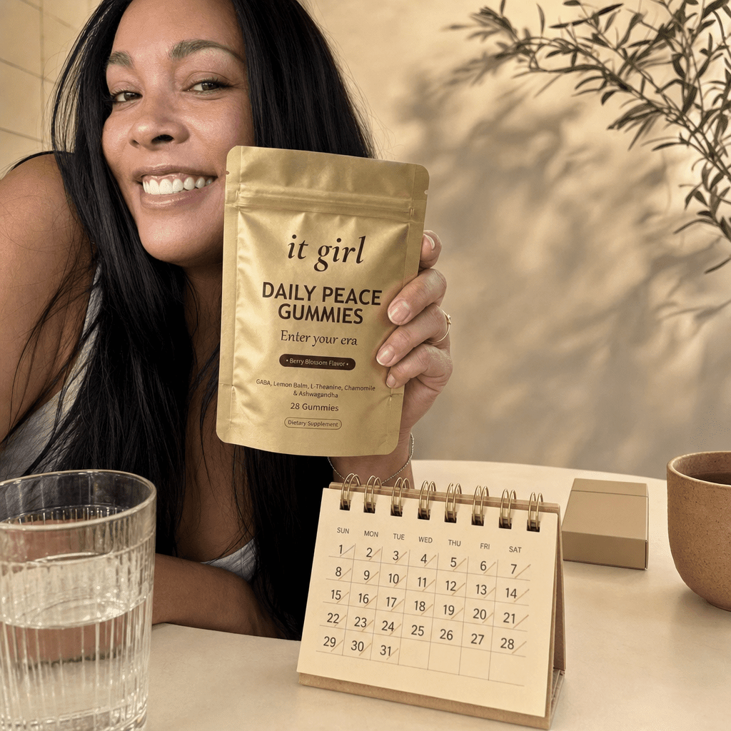 The palm-sized gold It Girl Daily Peace pouch and a month calendar in sharp focus on a cream surface, one plain unbranded cigarette pack soft-focused behind them, a whole month of calm for less than the habit costs