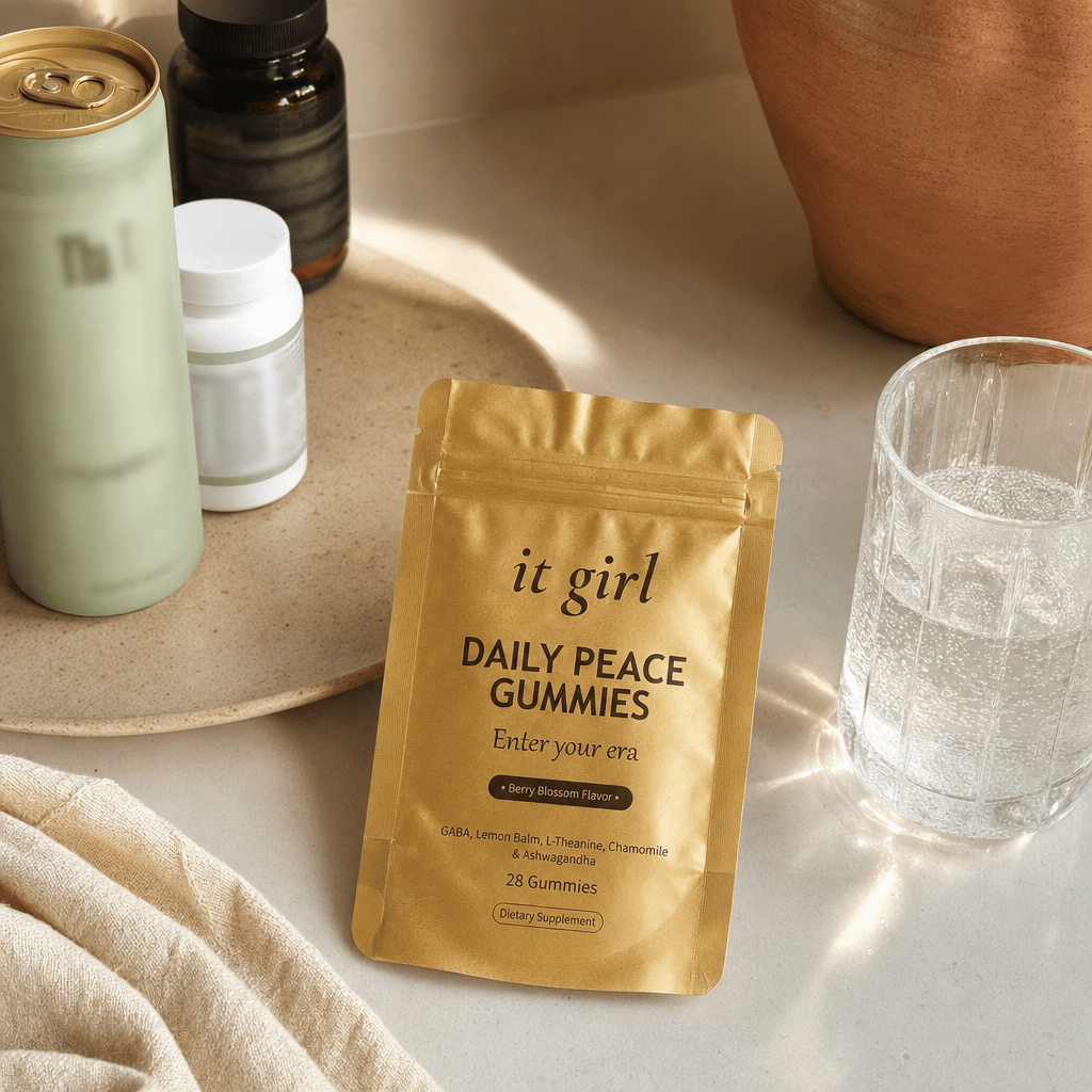 Cream counter of the abandoned swaps, an alcohol-free wine bottle, an adaptogen drink can, a magnesium bottle and a melatonin bottle pushed aside, the gold Daily Peace pouch chosen forward, no people