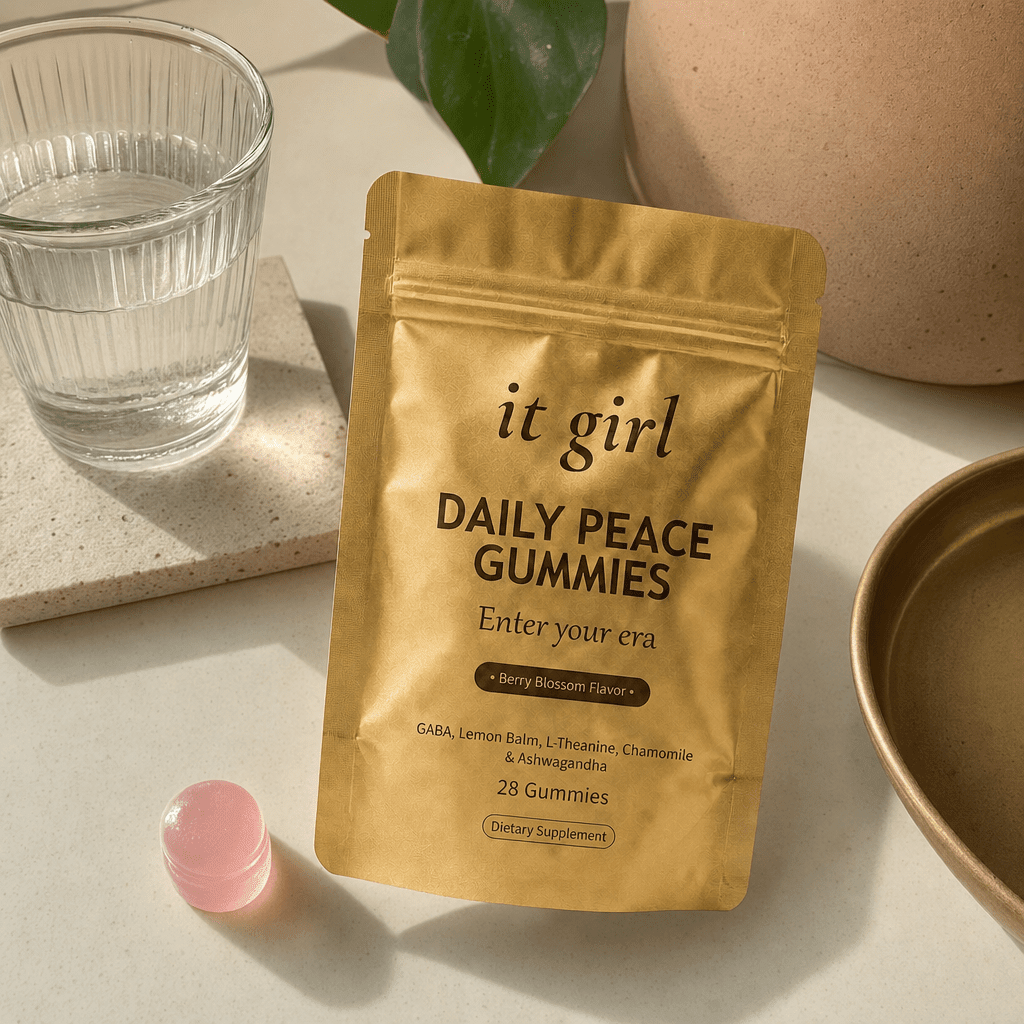 Open palm holding a single pink Daily Peace gummy beside the gold pouch and a glass of water on a cream counter, the GABA and L-Theanine calm signal handed back
